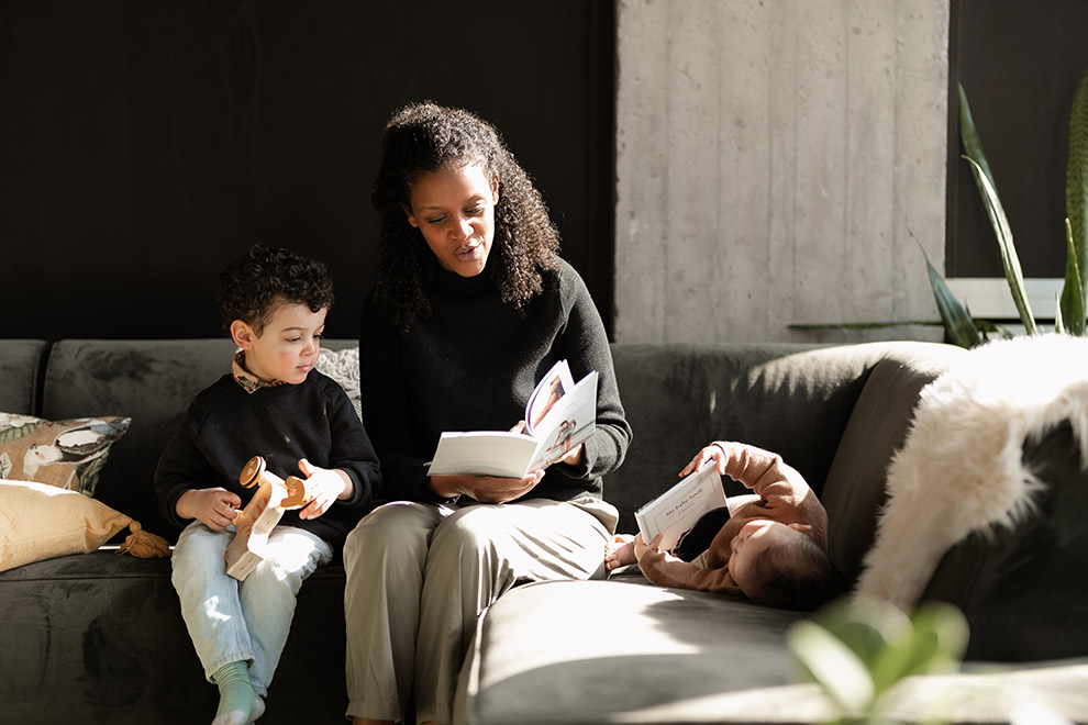 Mom reading from a Baby Diaries book with kids