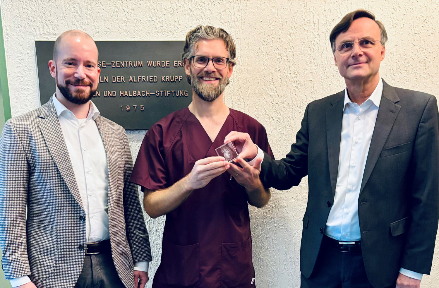 Mit einer symbolischen „Staffelstabübergabe“ in Form einer Nierenabbildung übergab Dr. Benno Kitsche (re.) gemeinsam mit Christian Thiemann, KfH-Geschäftsleiter Nord/West (li.) die ärztliche Leitung des KfH-Nierenzentrums Köln-Merheim an Dr. Felix Hundt. (Foto: KfH)