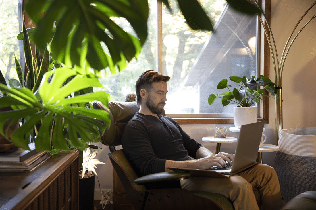 Male subject sitting with a laptop appears to be working from a serene environment