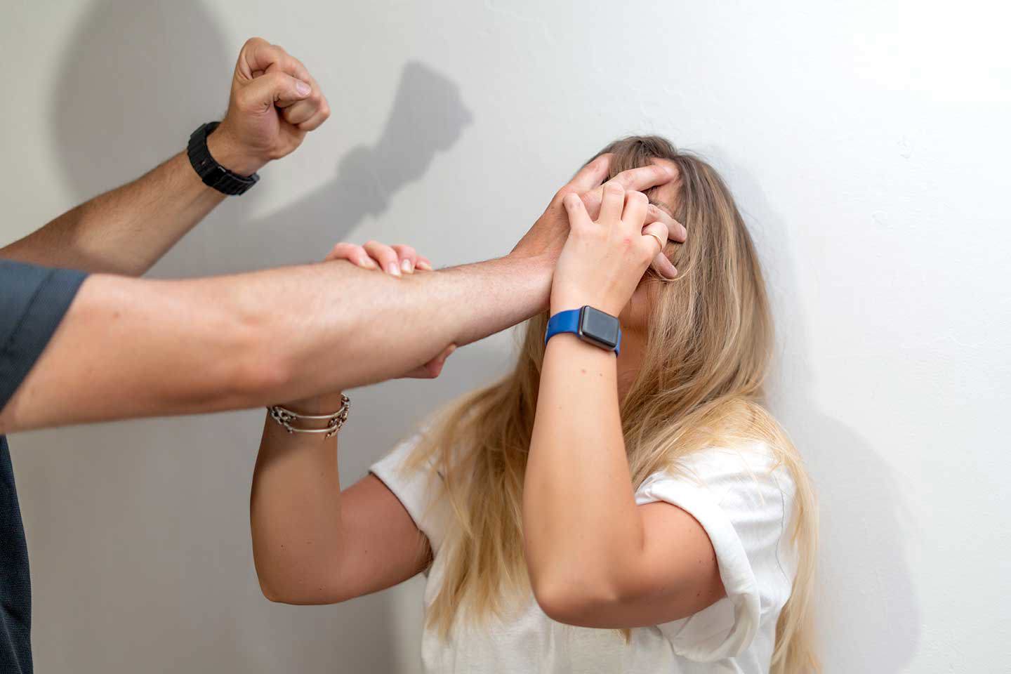 Ein Mann hält eine Frau gegen die Wand und scheint kurz davor zu sein, ihr Schaden zuzufügen.