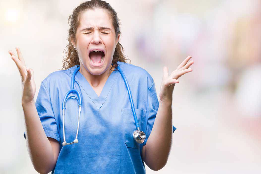 Eine junge Frau in medizinischer Kleidung schreit vor Angst und Verzweiflung, während sie ihre Hände nach oben wirft.