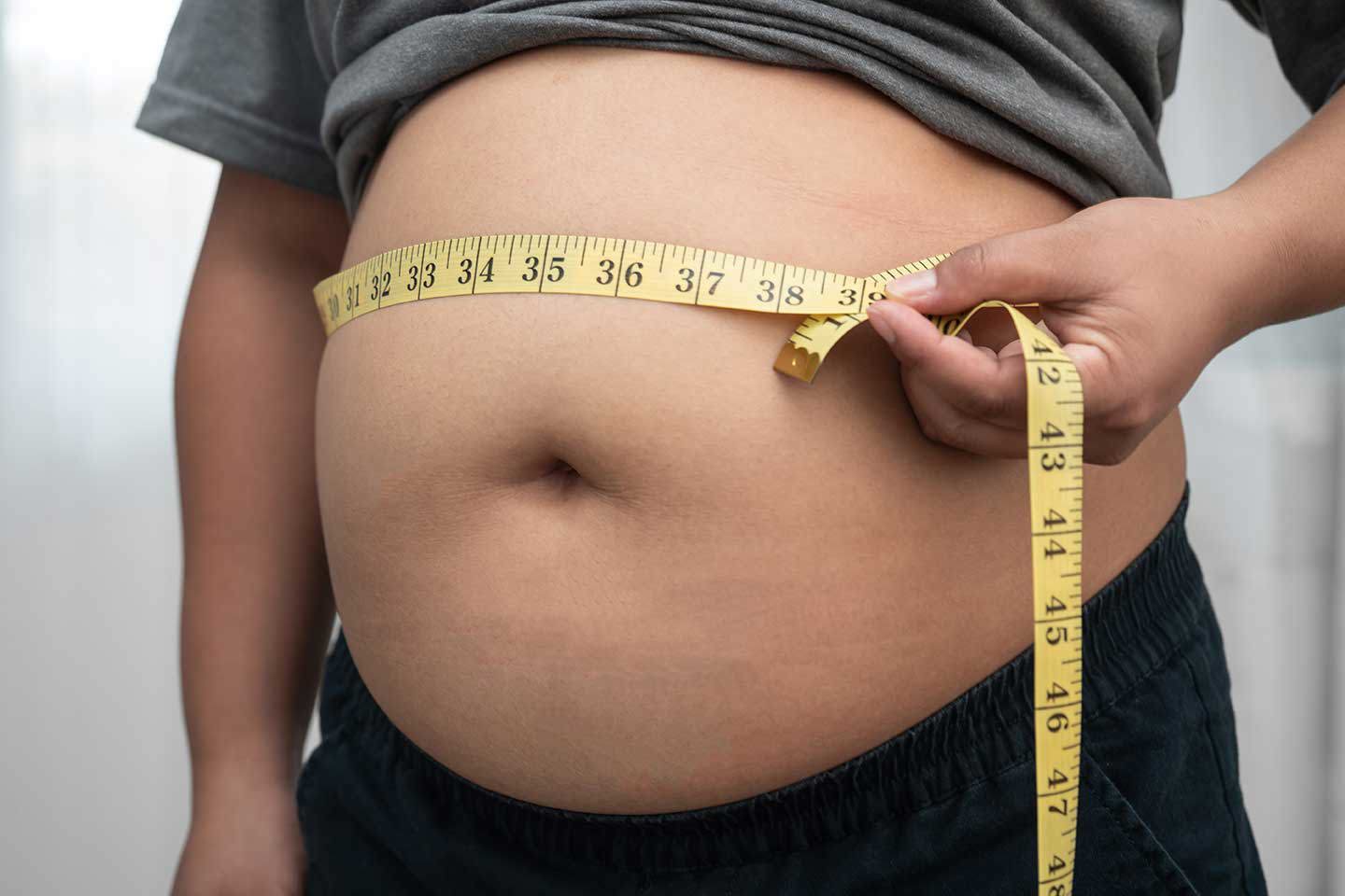 “Person measuring their waist circumference with a tape measure.”