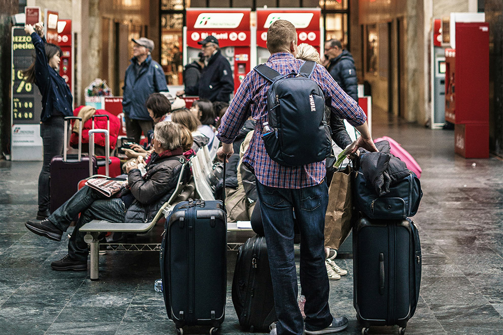 Een man staat op het vliegveld met zijn baggage te wachten.