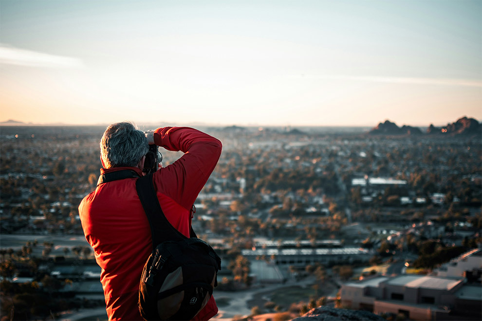 A man takes pictures of a city while overlooking it from above.