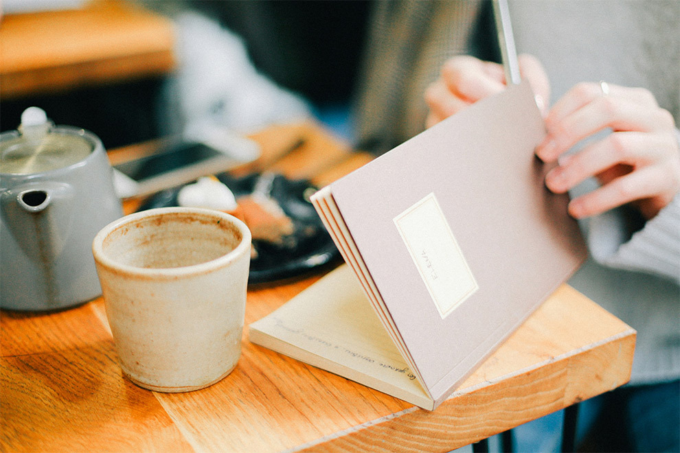 A woman writes in her journal with a cup of tea.