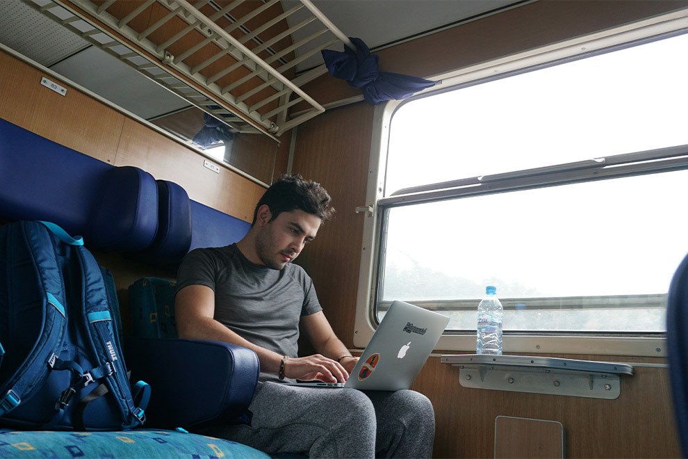 Een man werkt in een trein op zijn laptop.