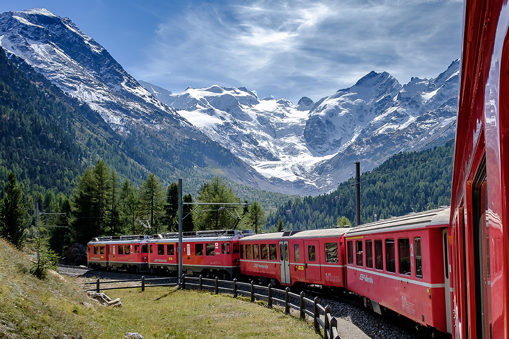 Rode trein rijdt door Zwitserse bergtoppen