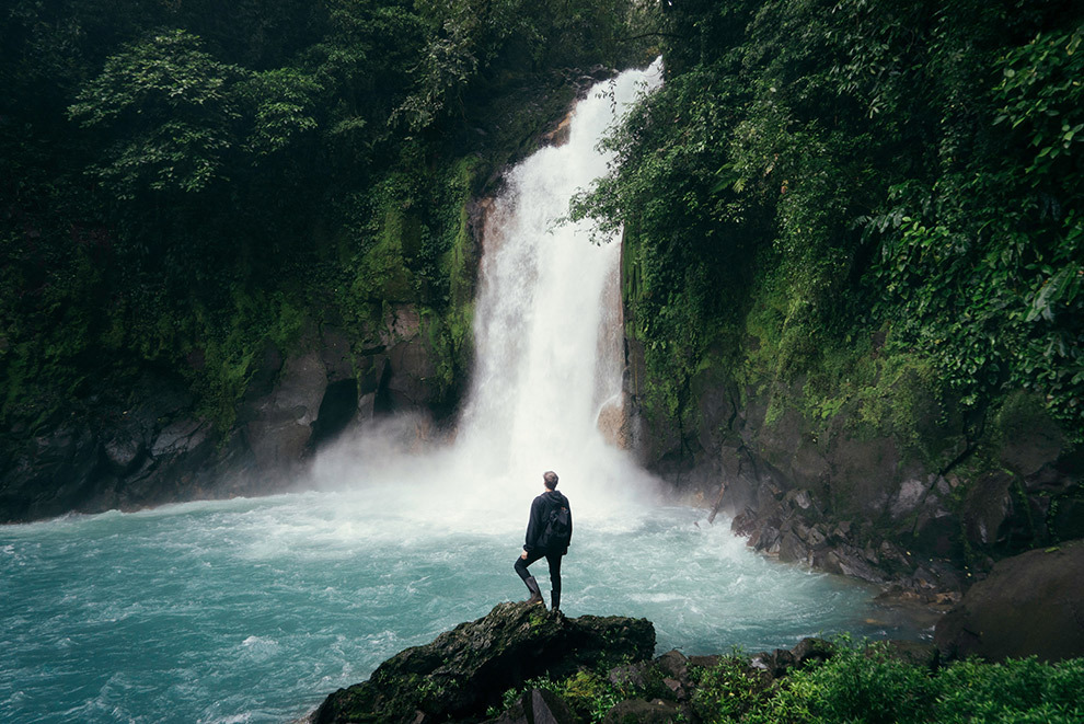 Traveler standing in front of waterfall 