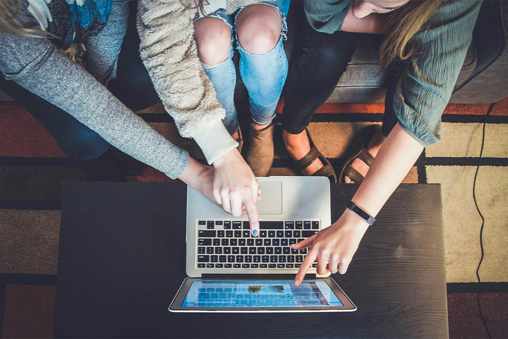 Drie vrouwen kijken samen naar een laptop.