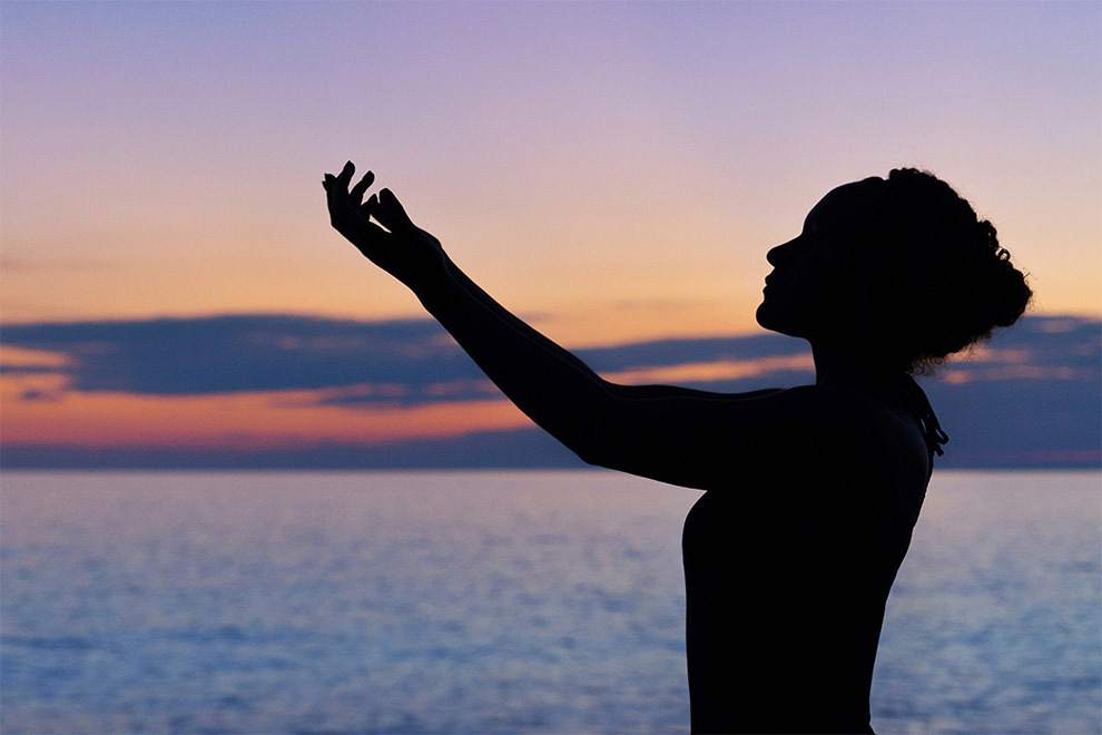 A woman practicing yoga at sunset.