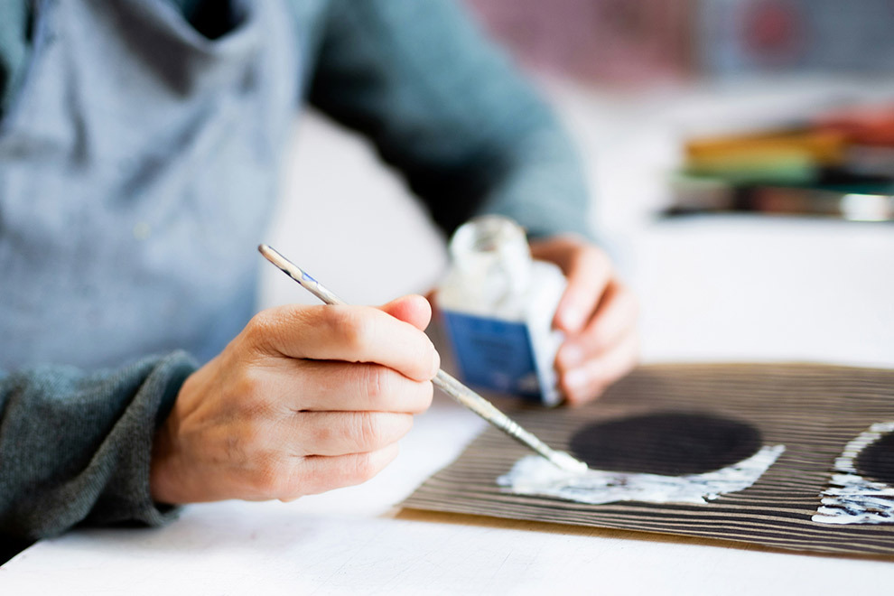 A person painting on cardboard.