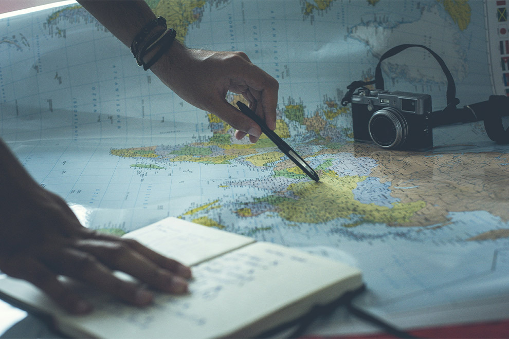 A person looking at a world map and making notes in a notebook.