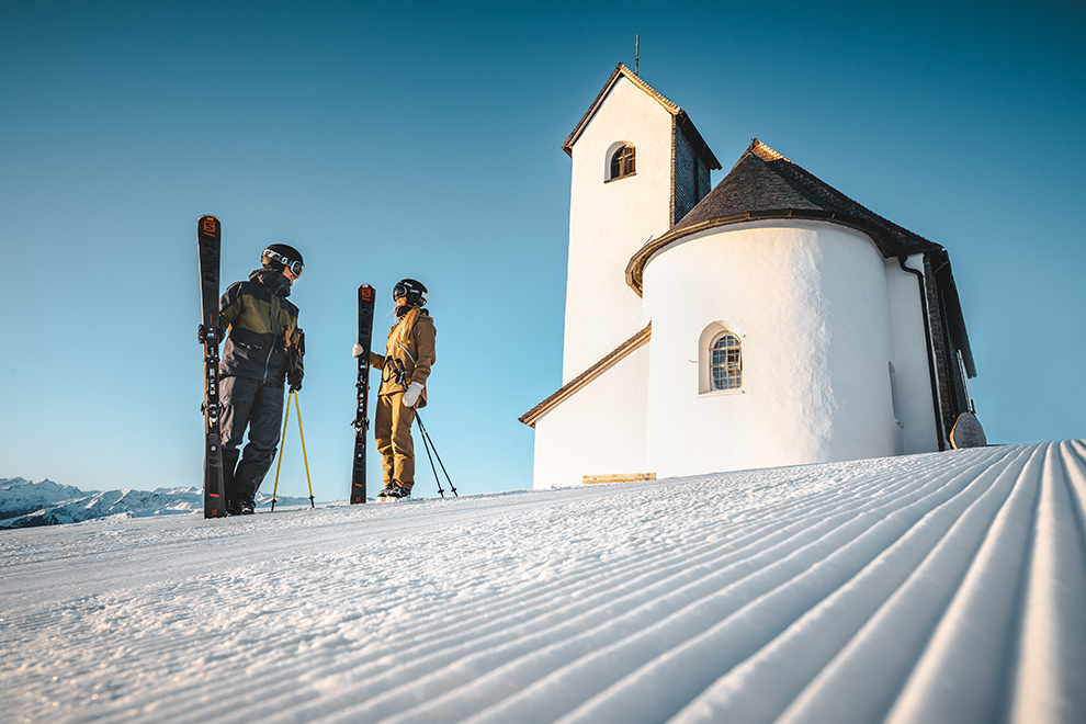 Skiërs voor het witte Salvenkerkje in Oostenrijk