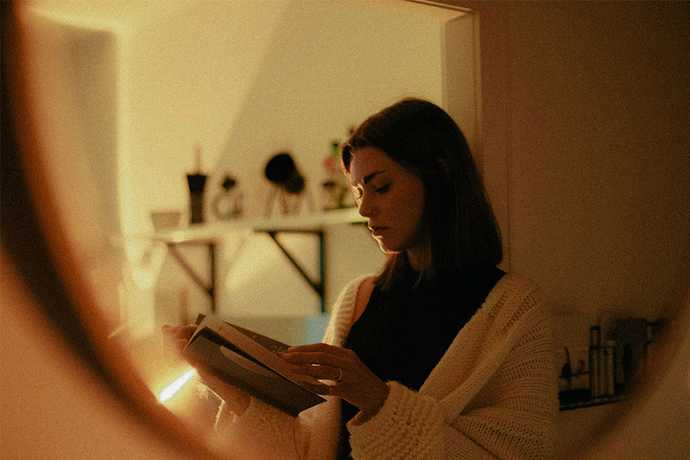 A woman reads a book, looking reflective.